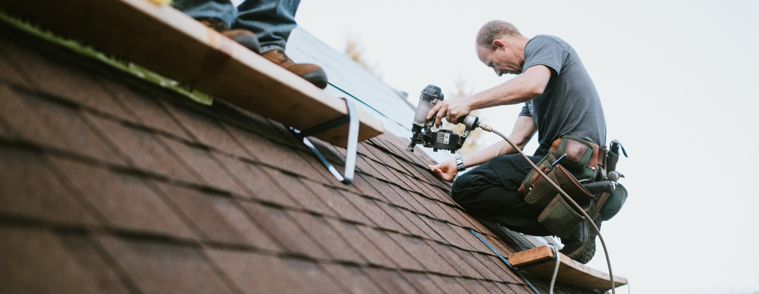 Two roofing technicians working on a house